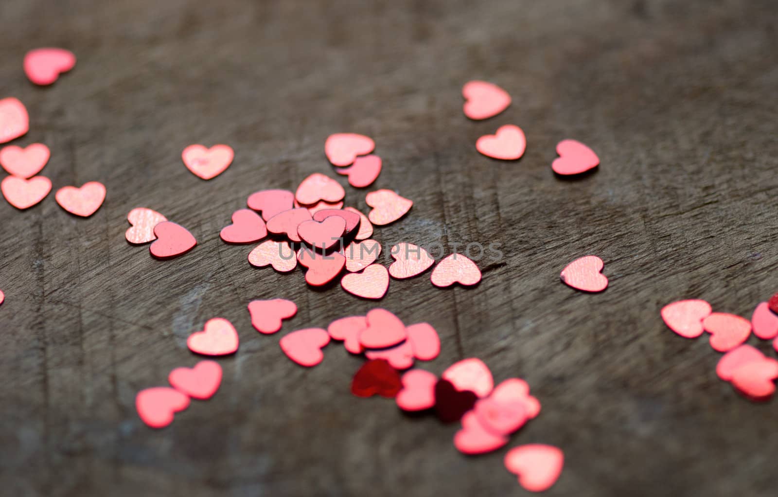 A heart made of chocolat on a old wooden table with small glitter hearts