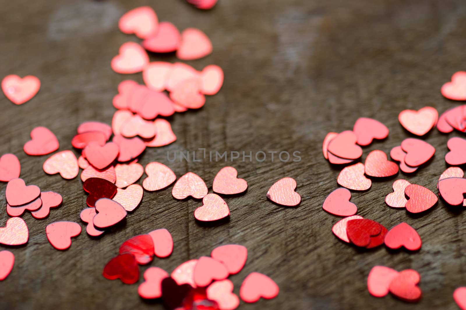 A heart made of chocolat on a old wooden table with small glitter hearts