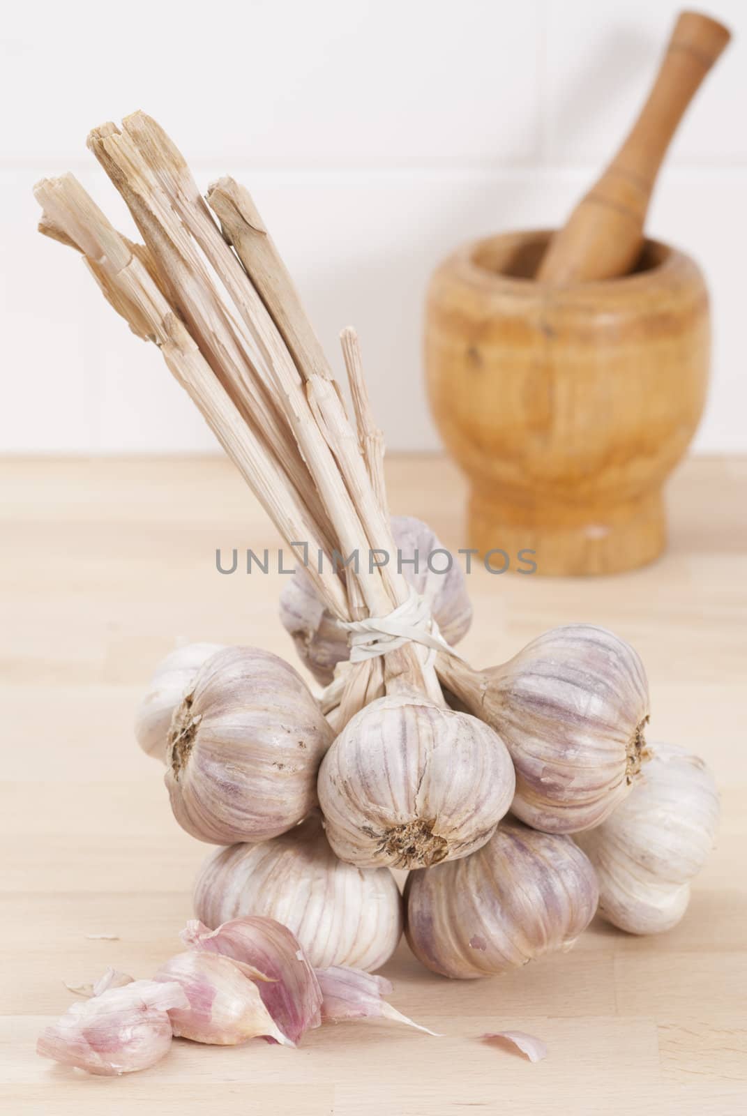 Bunch of tied garlic on wooden kitchen work surface.