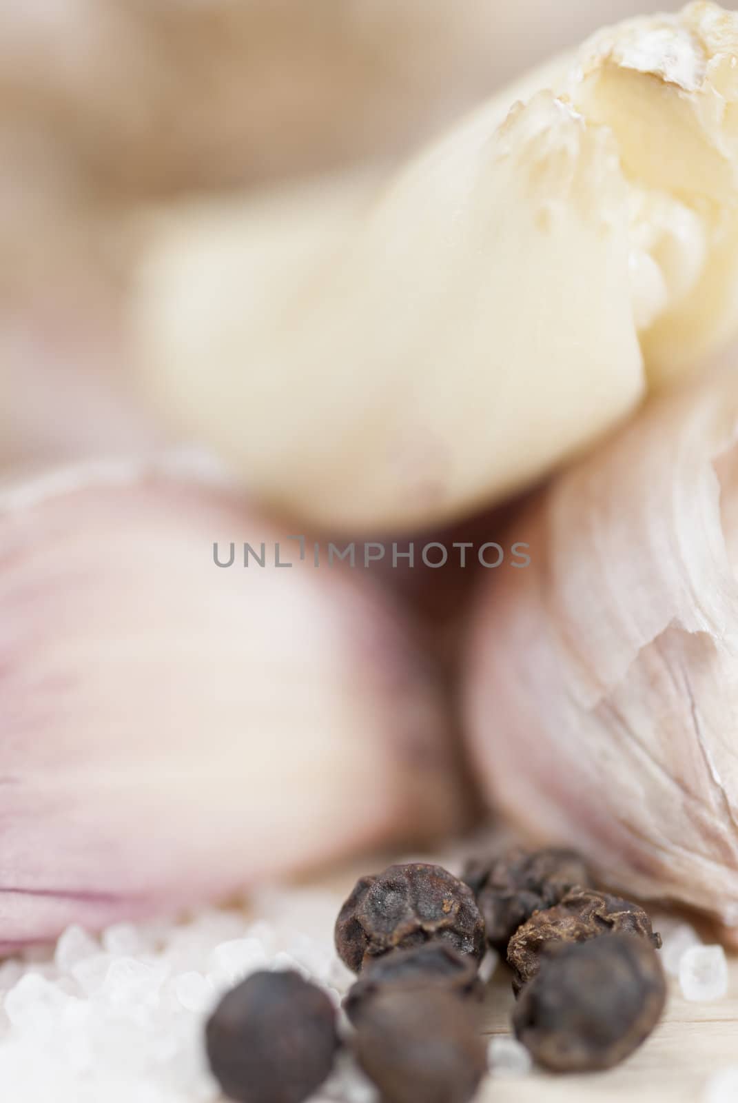 Garlic cloves, peppercorns & salt on wooden surface.