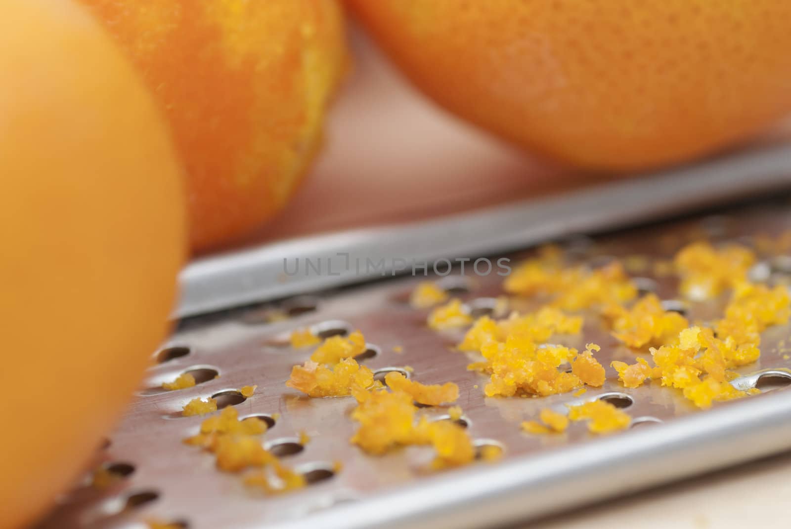 Grater and citrus zest on wooden kitchen surface.