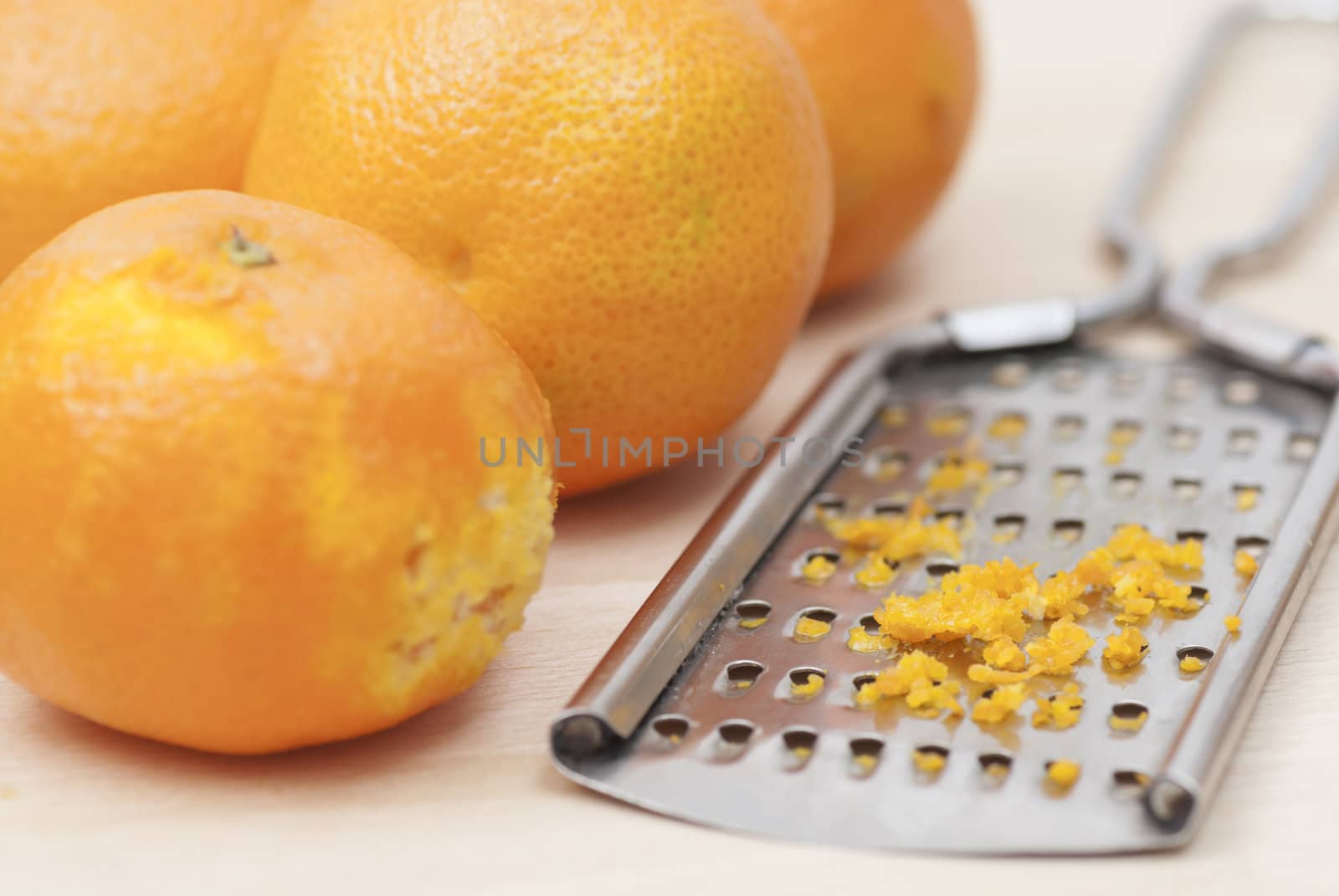 Grater and citrus zest on wooden kitchen surface.