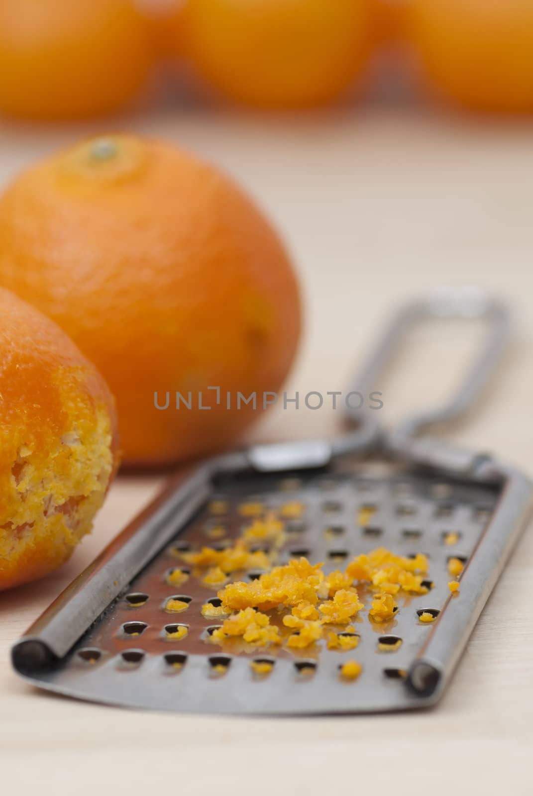 Grater and citrus zest on wooden kitchen surface.