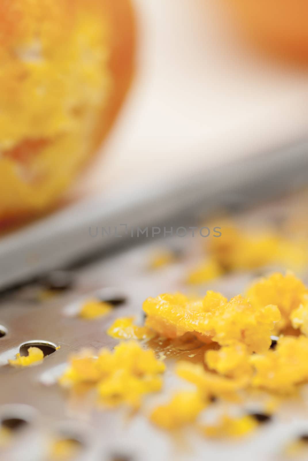 Grater and citrus zest on wooden kitchen surface.