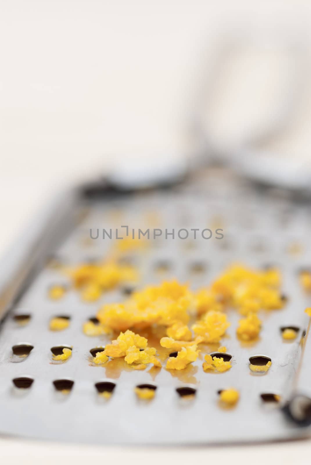 Grater and citrus zest on wooden kitchen surface.