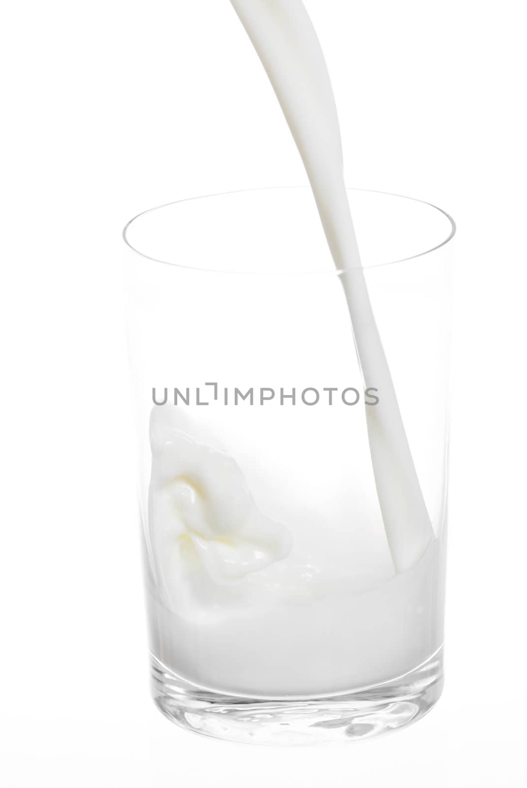 Milk pouring into small glass. White background.