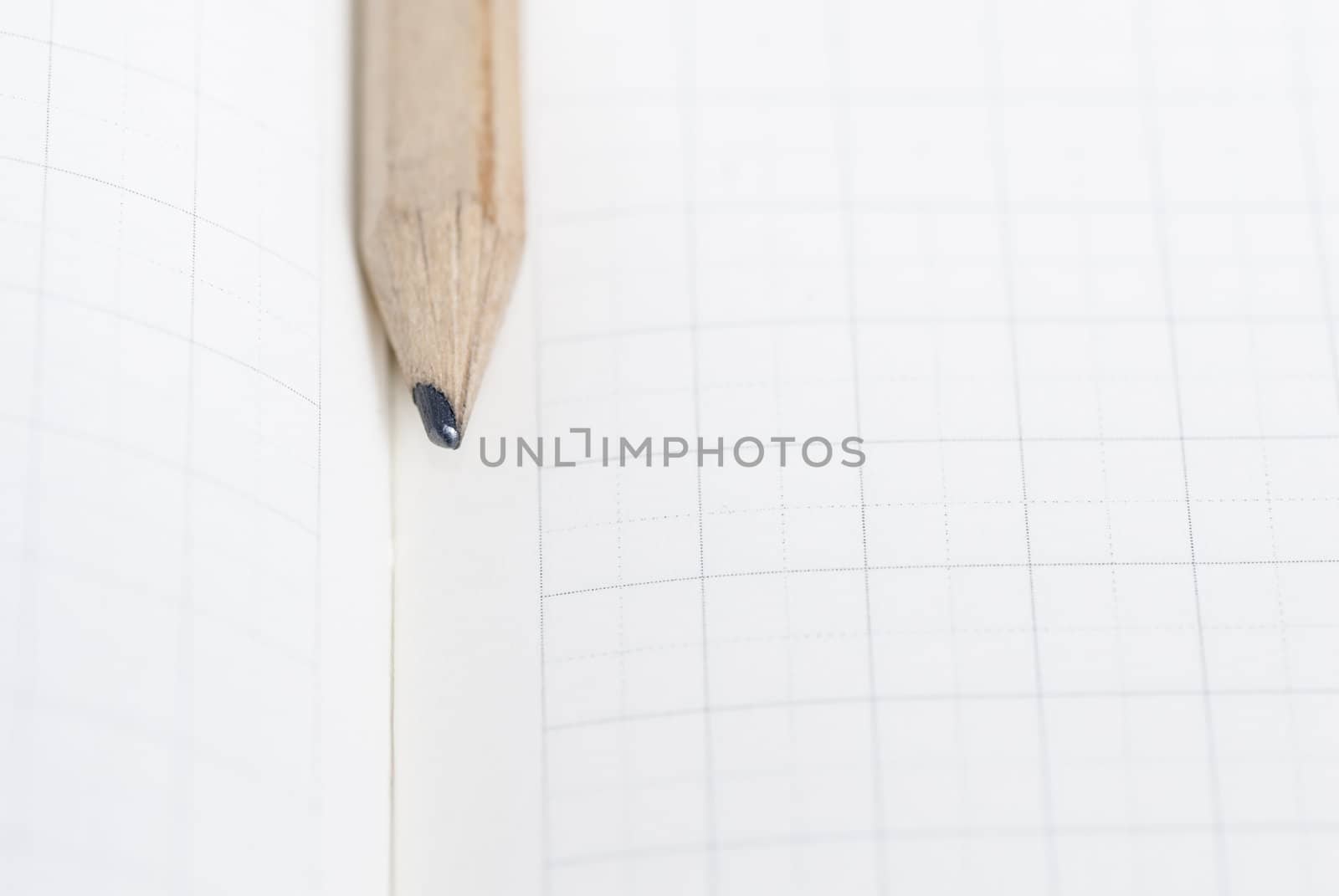 Pencil resting on blank squared note paper.