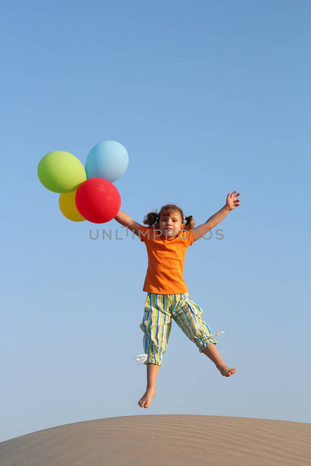 happy little girl jumping with balloons