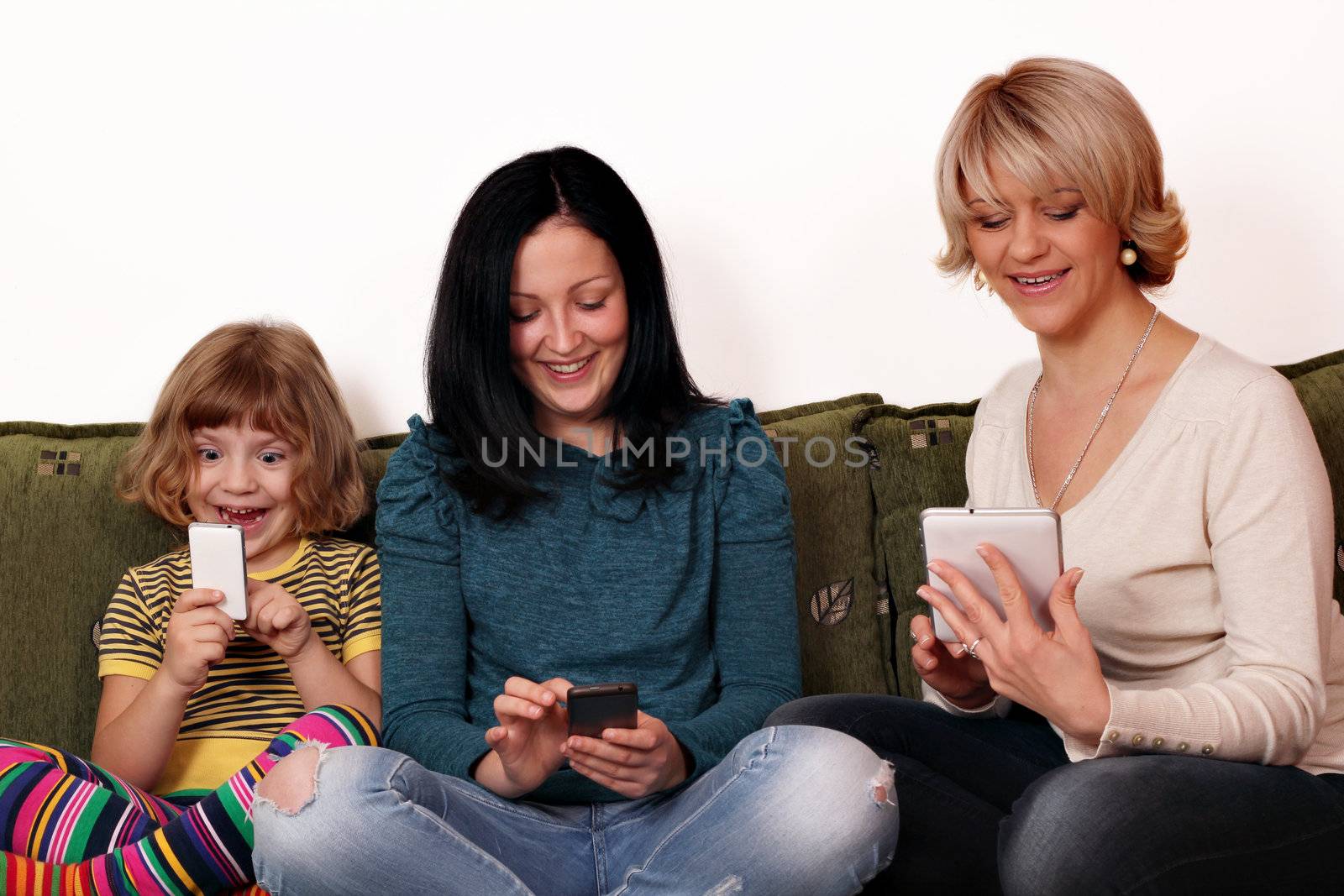 happy mother and daughters playing with smart phones and tablet by goce