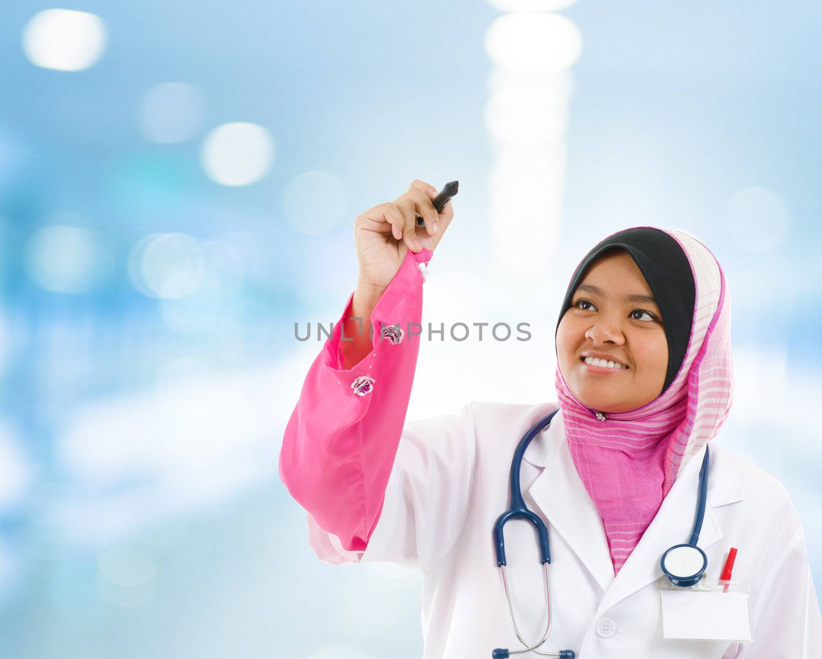 Southeast Asian Muslim medical student sketching on transparent screen, hospital blue background