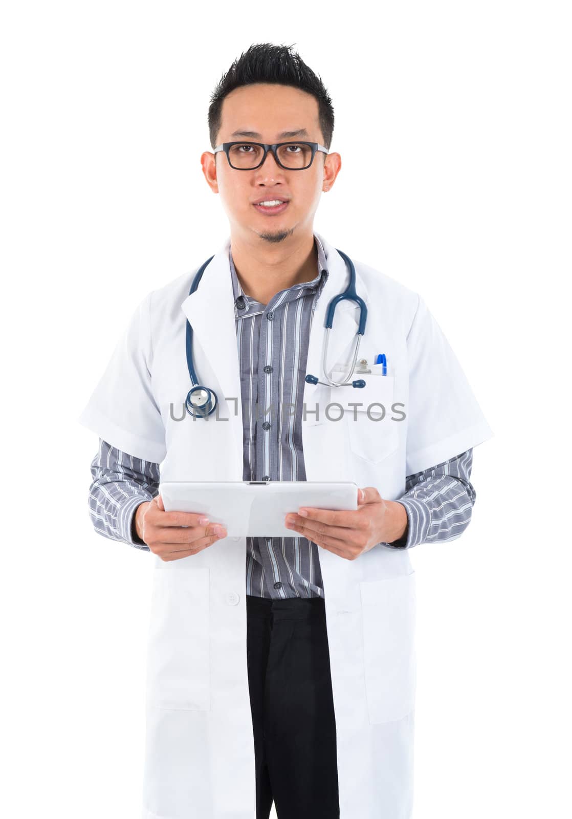 Southeast Asian medical doctor. Serious male medical doctor holding a tablet computer standing on white background.