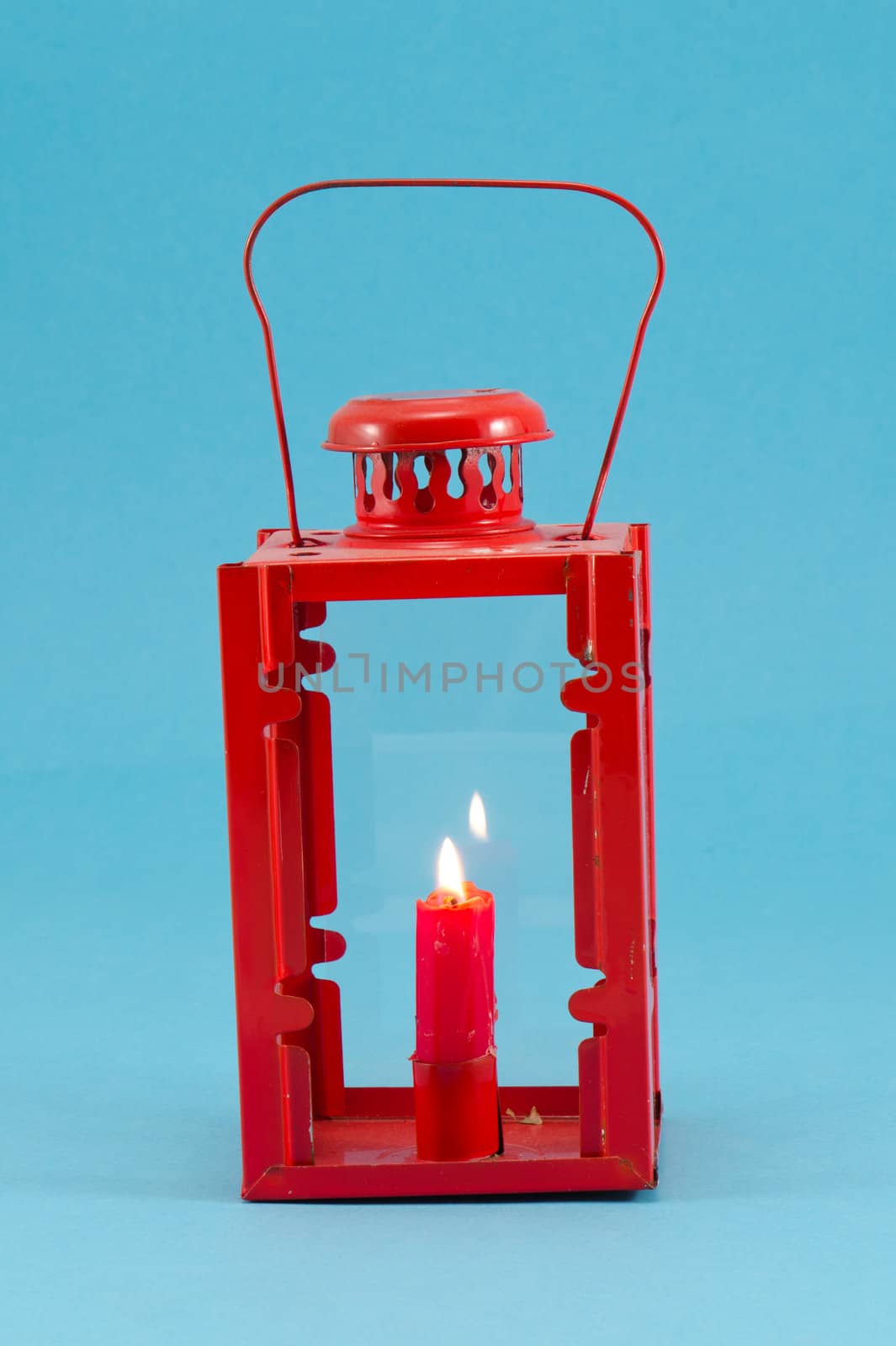 steel red retro candlestick lamp with handle and candle burn on blue background.