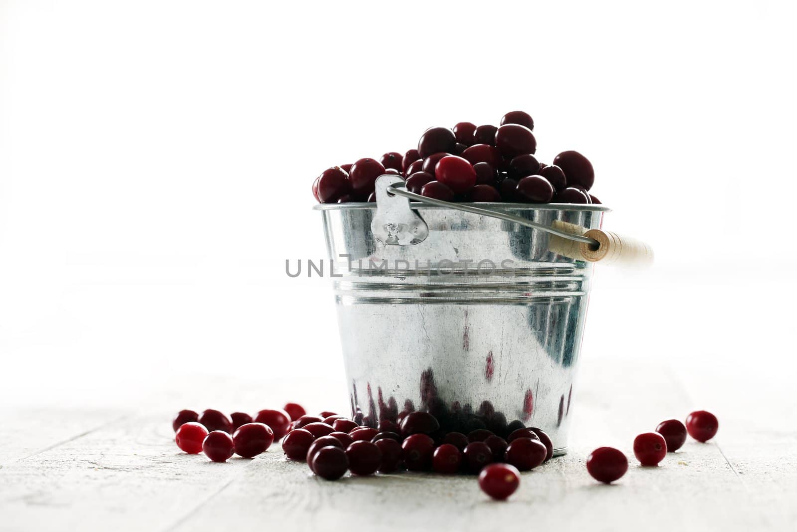 Fresh cranberries in a silver bucket on a white wooden table