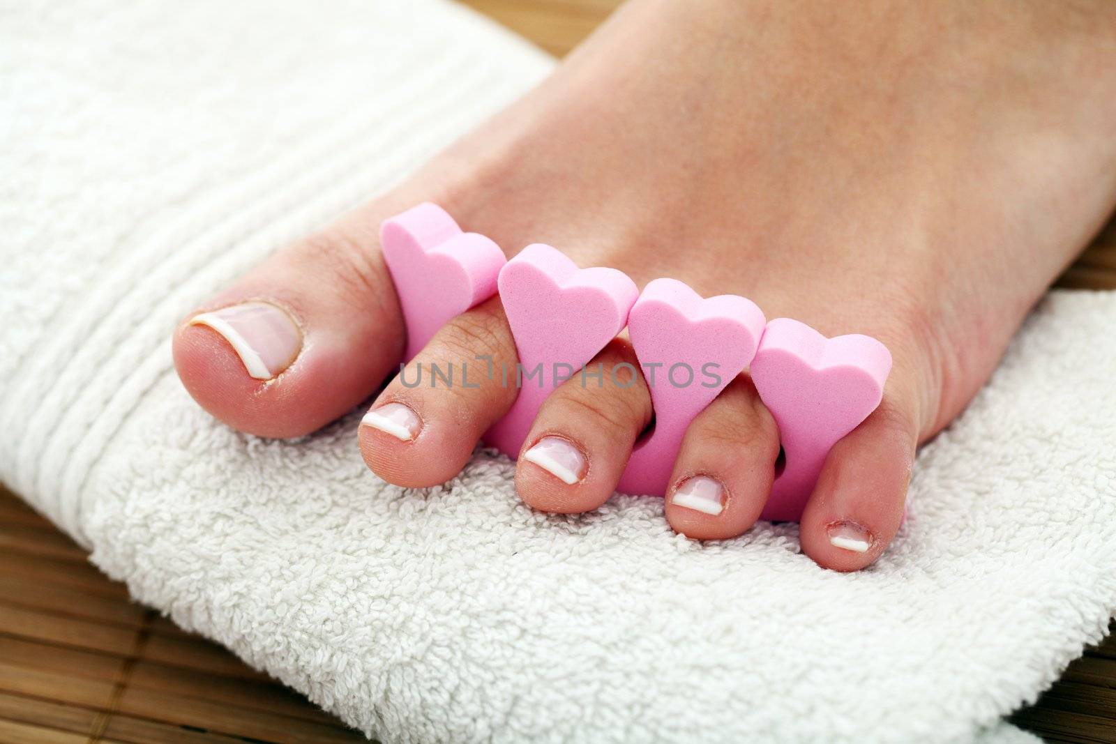 Beautiful foot with french pedicure on white towel