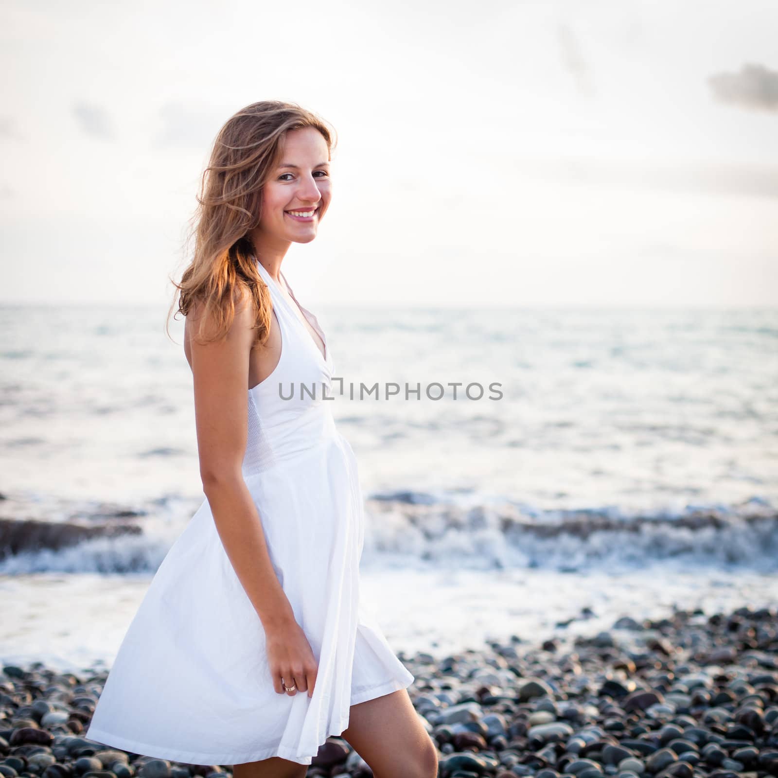 Young woman on the beach enjoying a warm summer evening, relaxin by viktor_cap