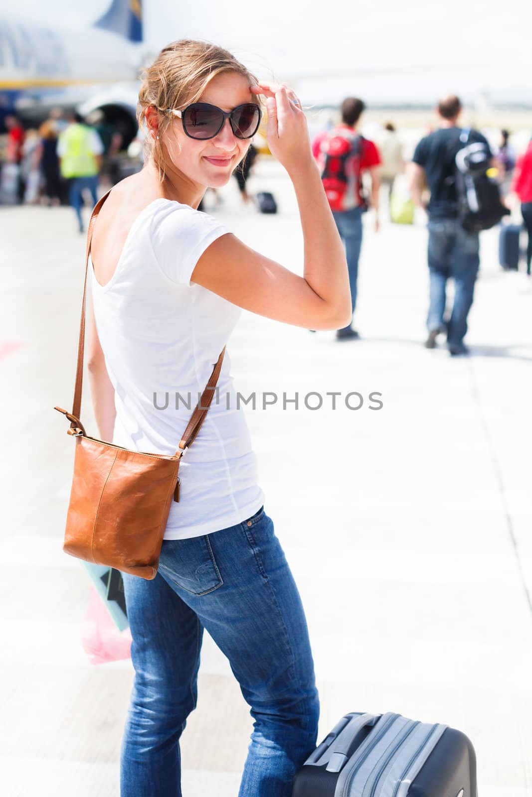 Departure - young woman at an airport about to board an aircraft on a sunny summer day