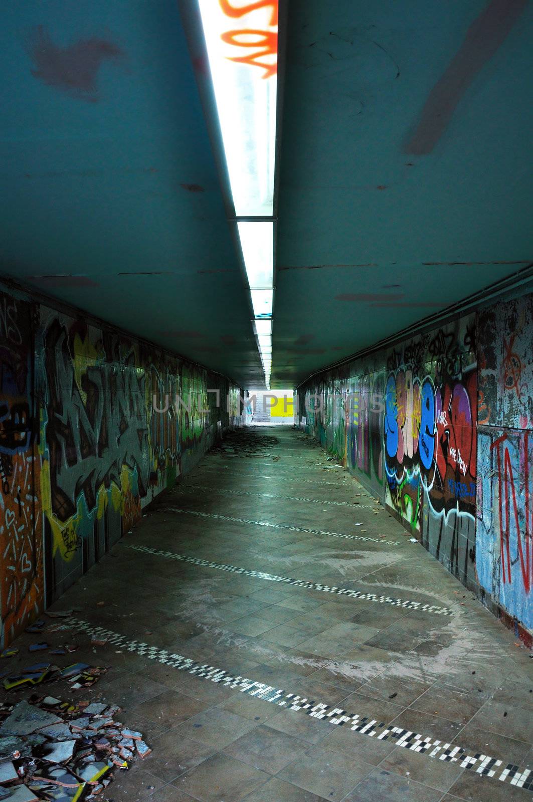 Dirty pedestrian underpass under the motorway. Smashed tiles and smudged walls.