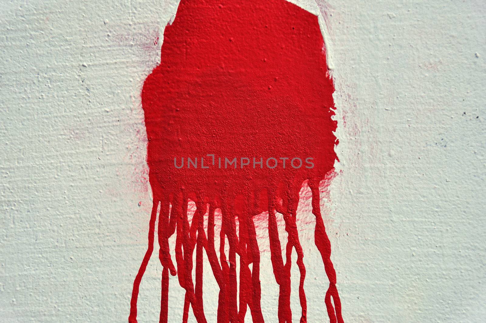 Red paint drips over textured white wall. Abstract background.