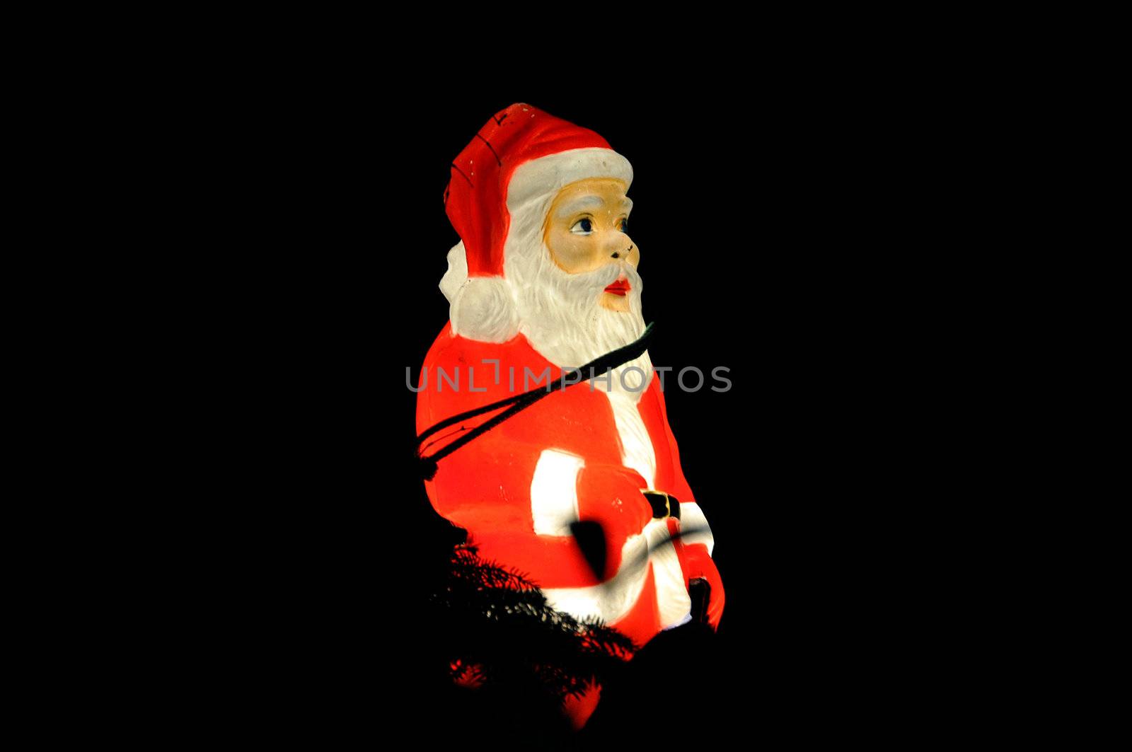 Santa Claus Christmas decorative illuminated figure on a tree at night.