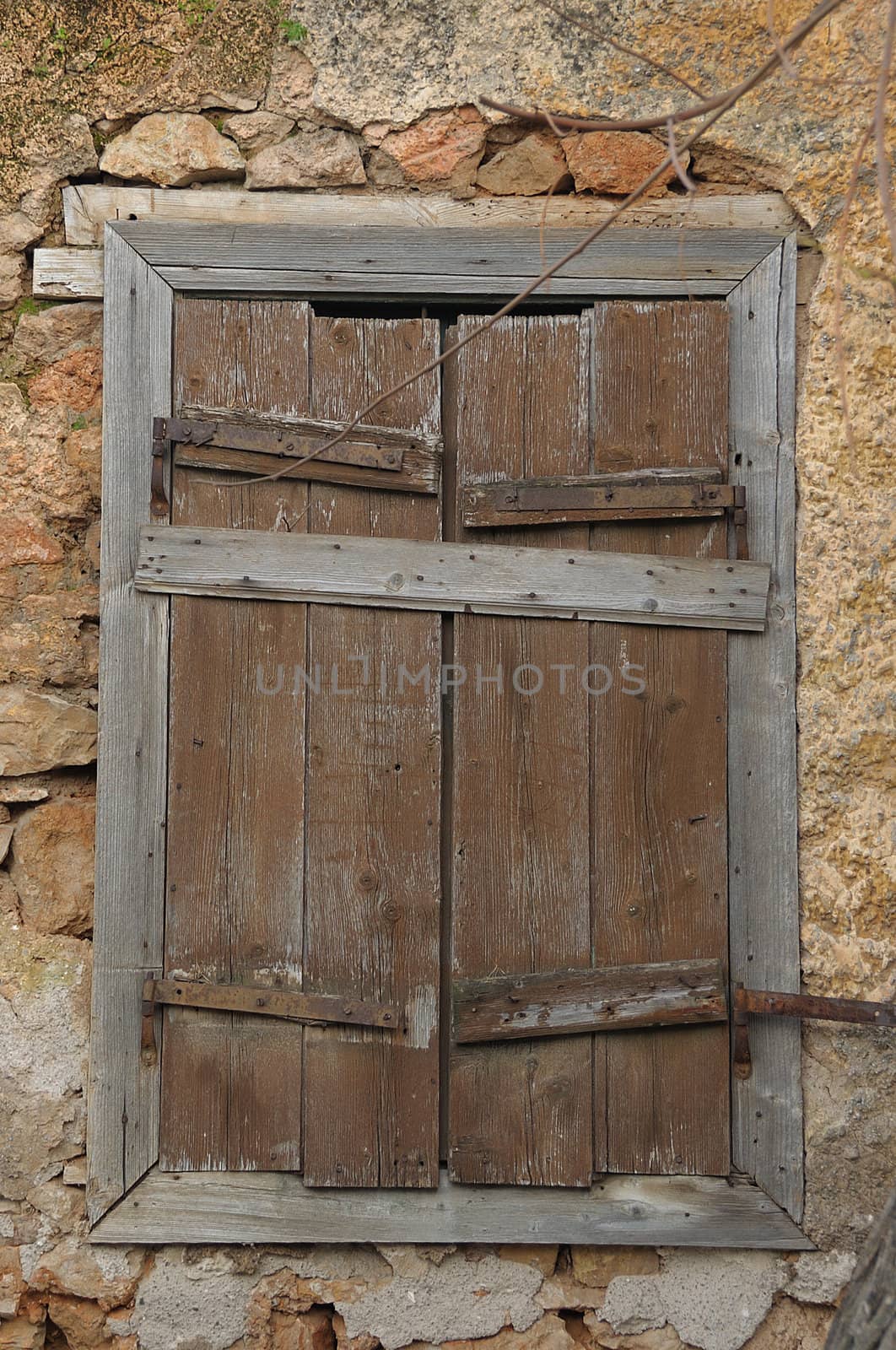 Boarded up wooden window shutter and weathered wall of derelict house.