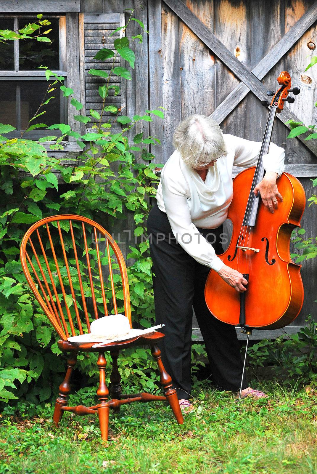 Mature female cellist with her instrument outside.