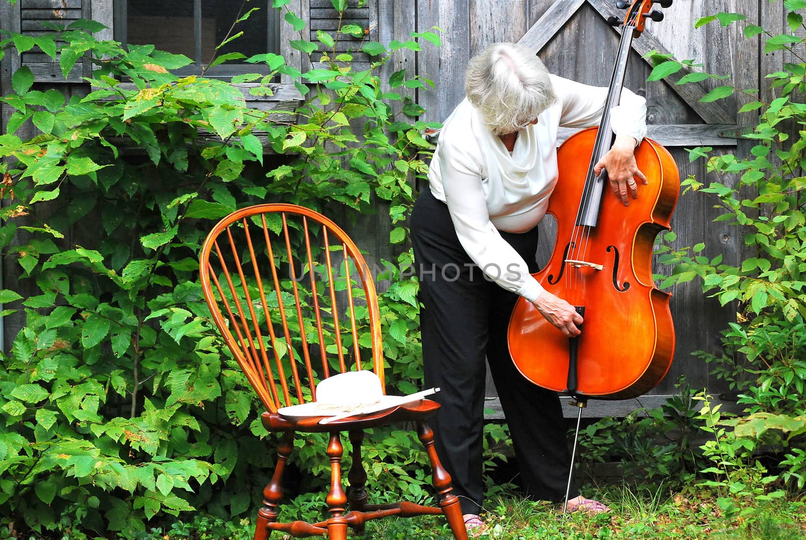 Mature female cellist with her instrument outside.