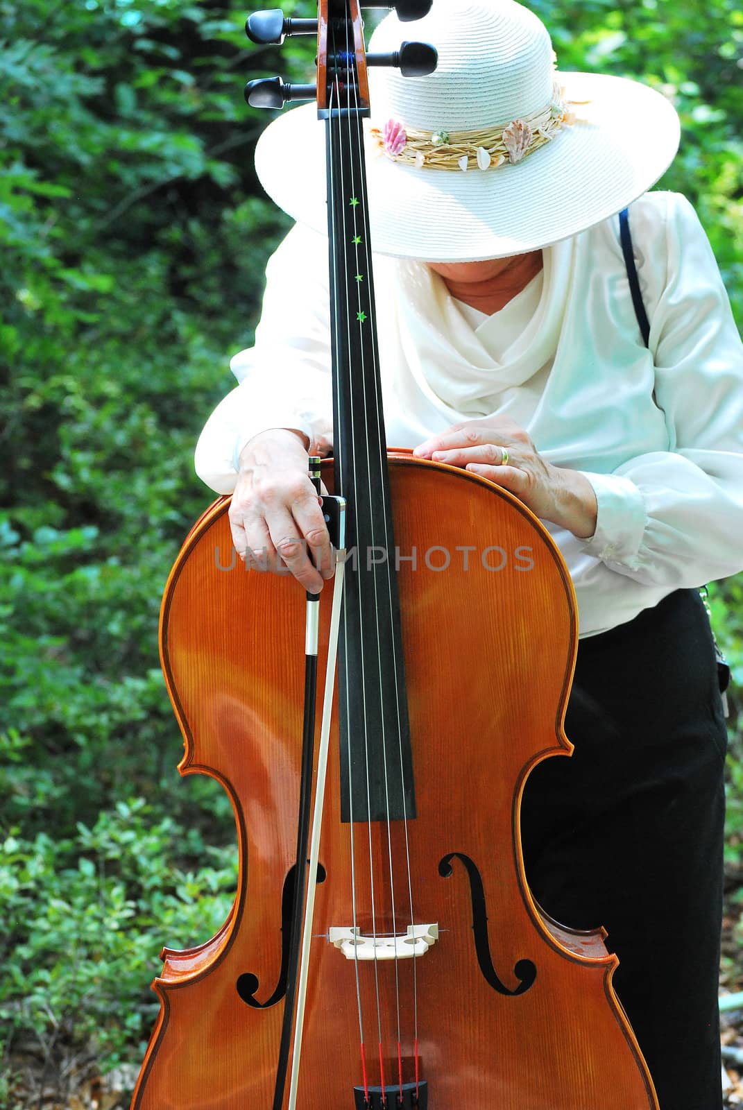 Mature female cellist with her instrument outside.