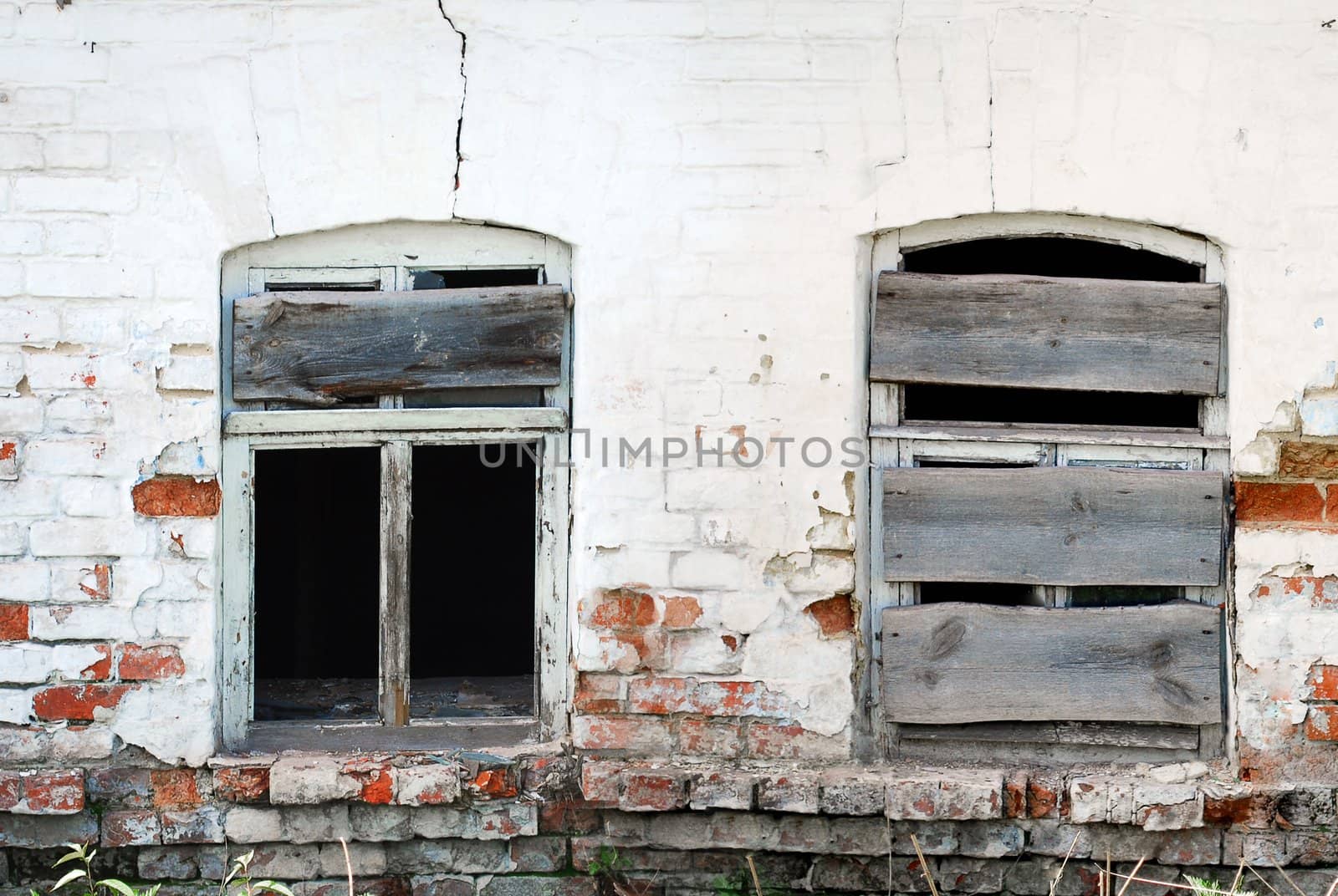 Two Cracked Broken Windows on Damaged Brick Wall in Abandoned House Building