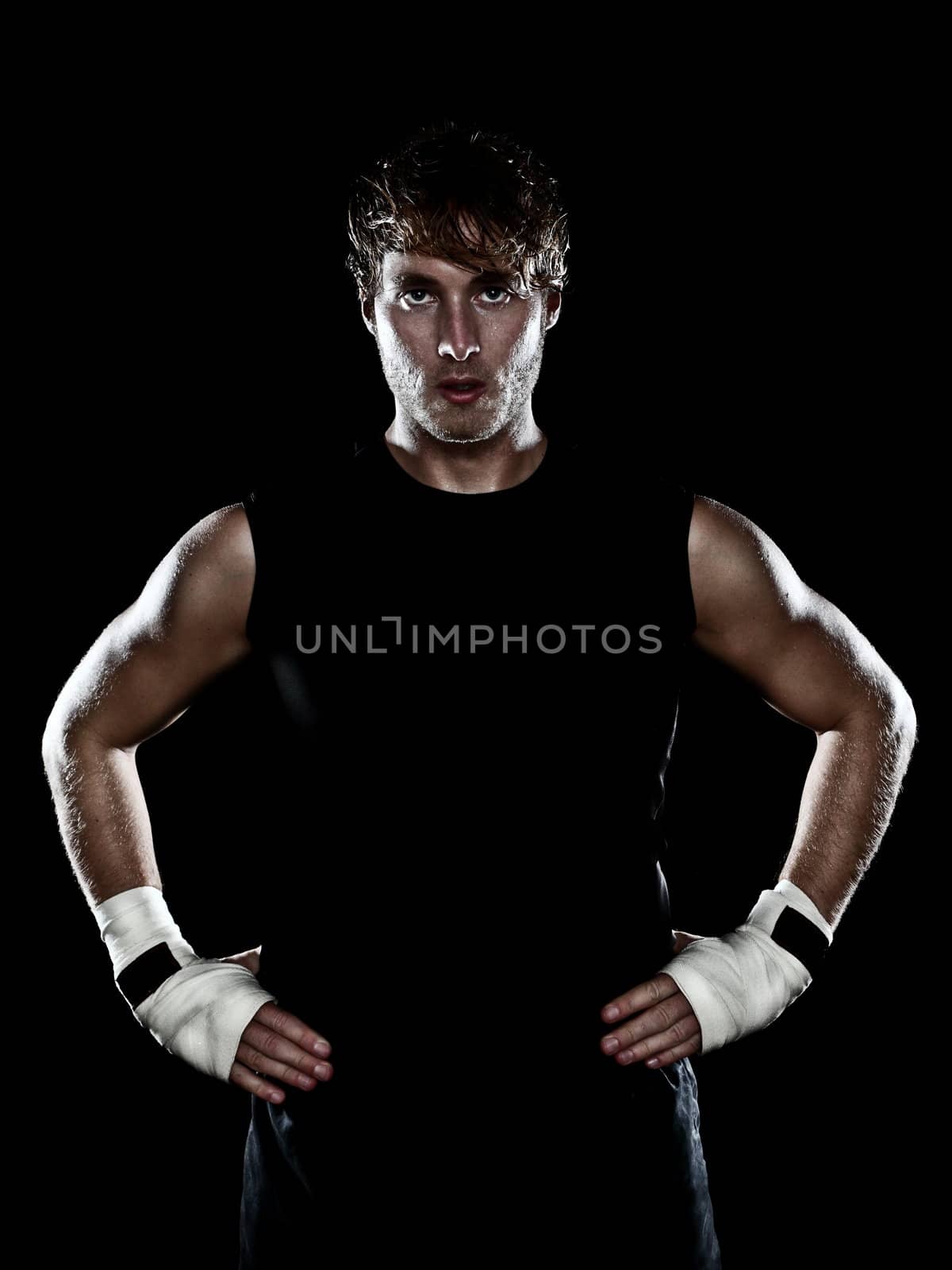 Fighter boxer standing staring strong on black background. Young masculine caucasian male athlete in his 20s.