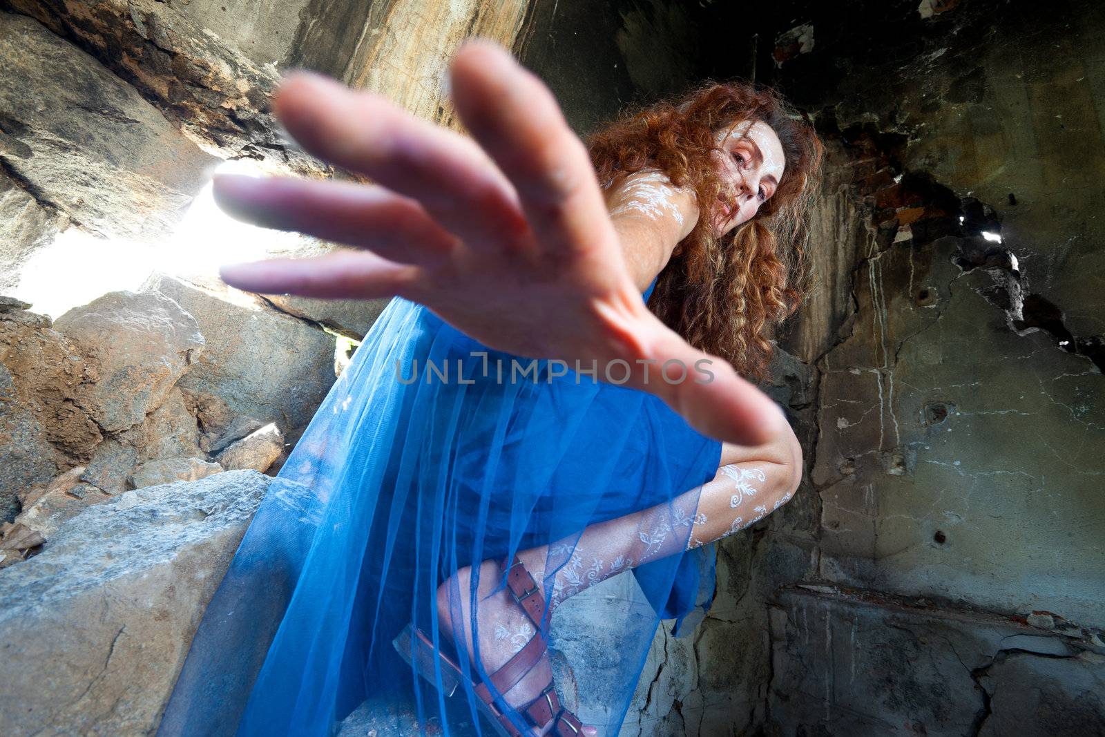 Woman with white body henna in abandoned building, reaching down to the camera