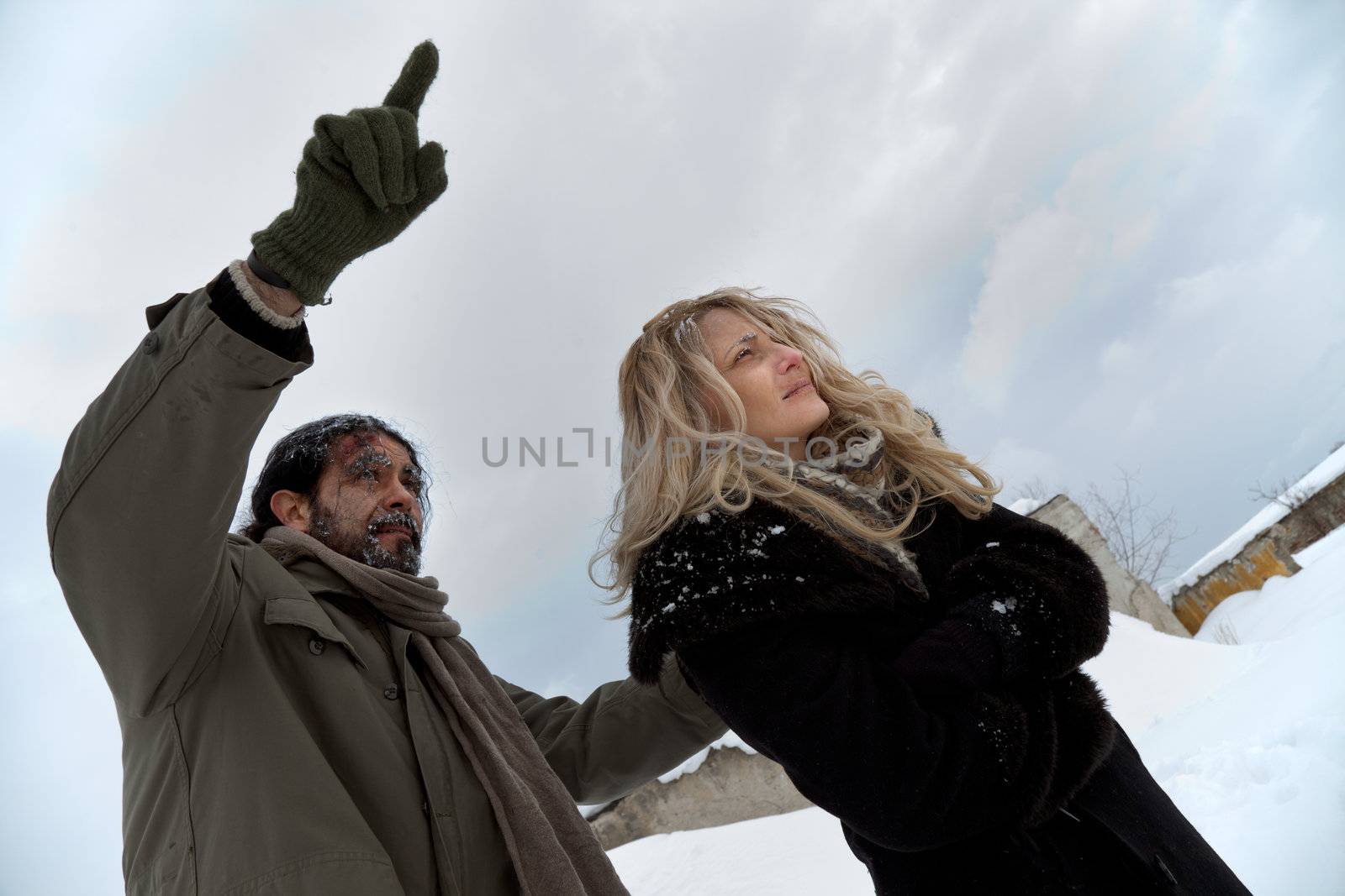 Homeless couple in winter time, male pointing forward