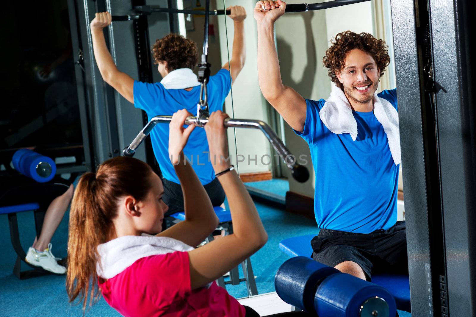 Friends working out together in a multi gym. Indoor gym shot