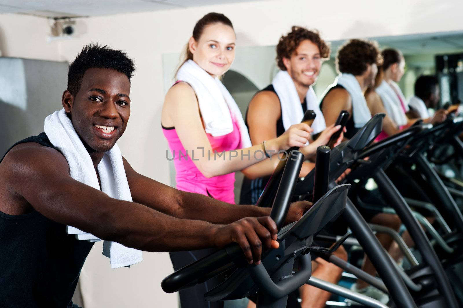 Energetic group working out together in a gym on elliptical