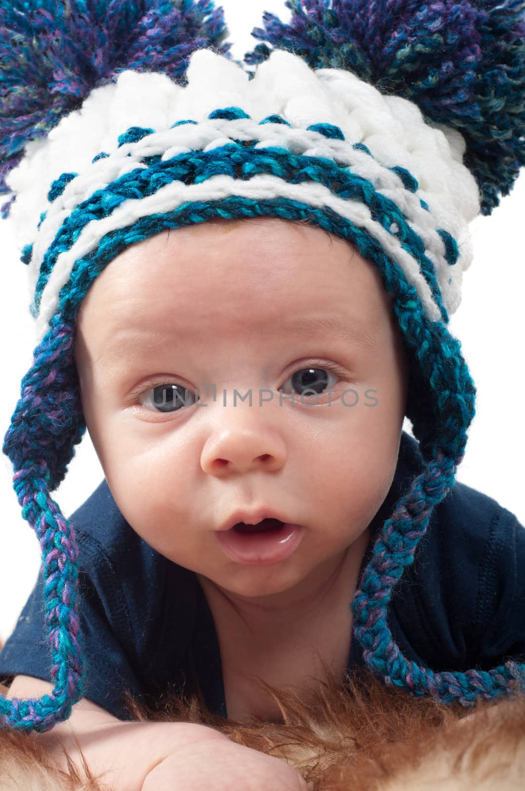 Shot of little baby in knitted hat lying on fur