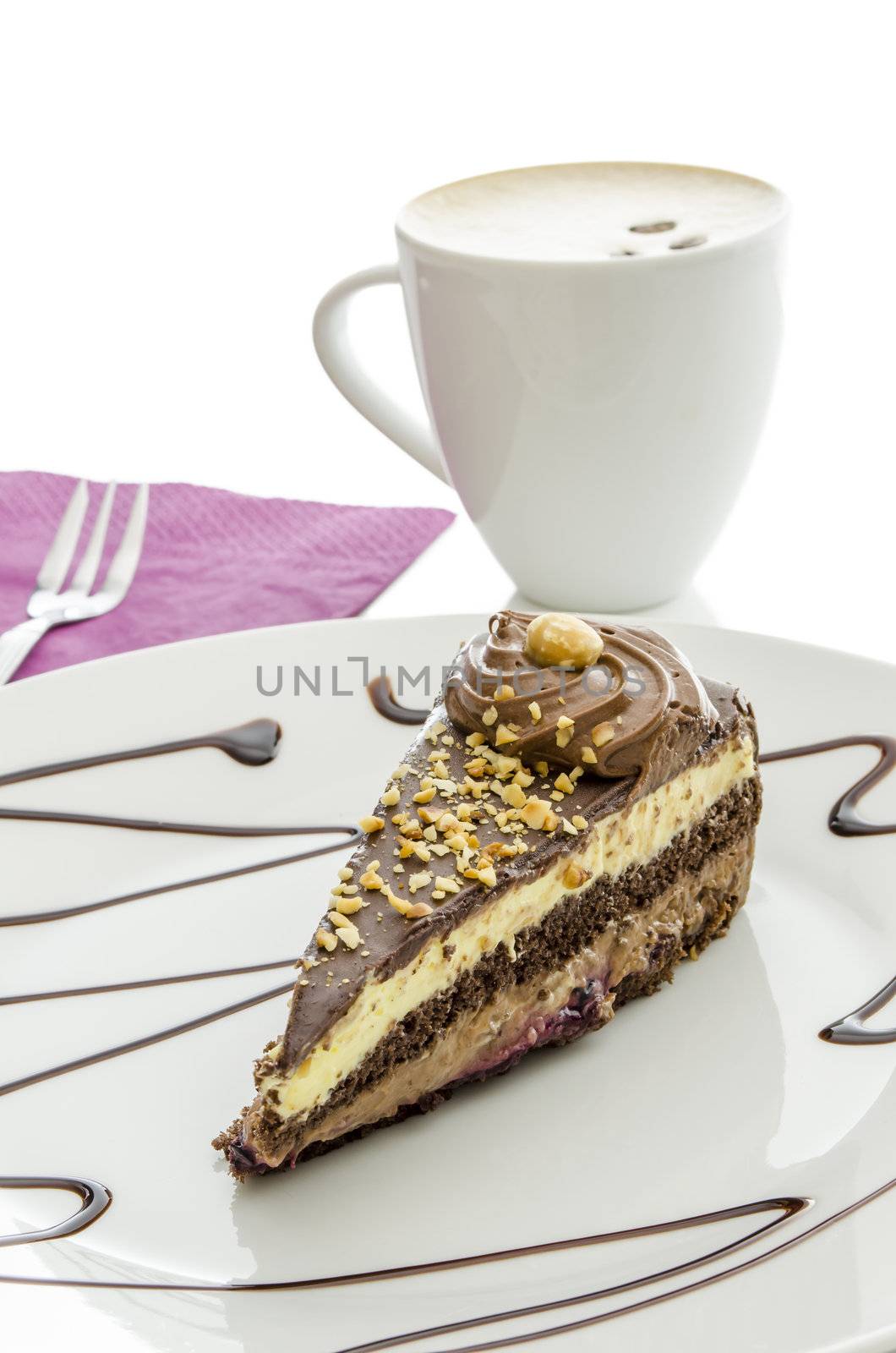 Chocolate cake served on a decorated plate. Coffee in a white cup in background.