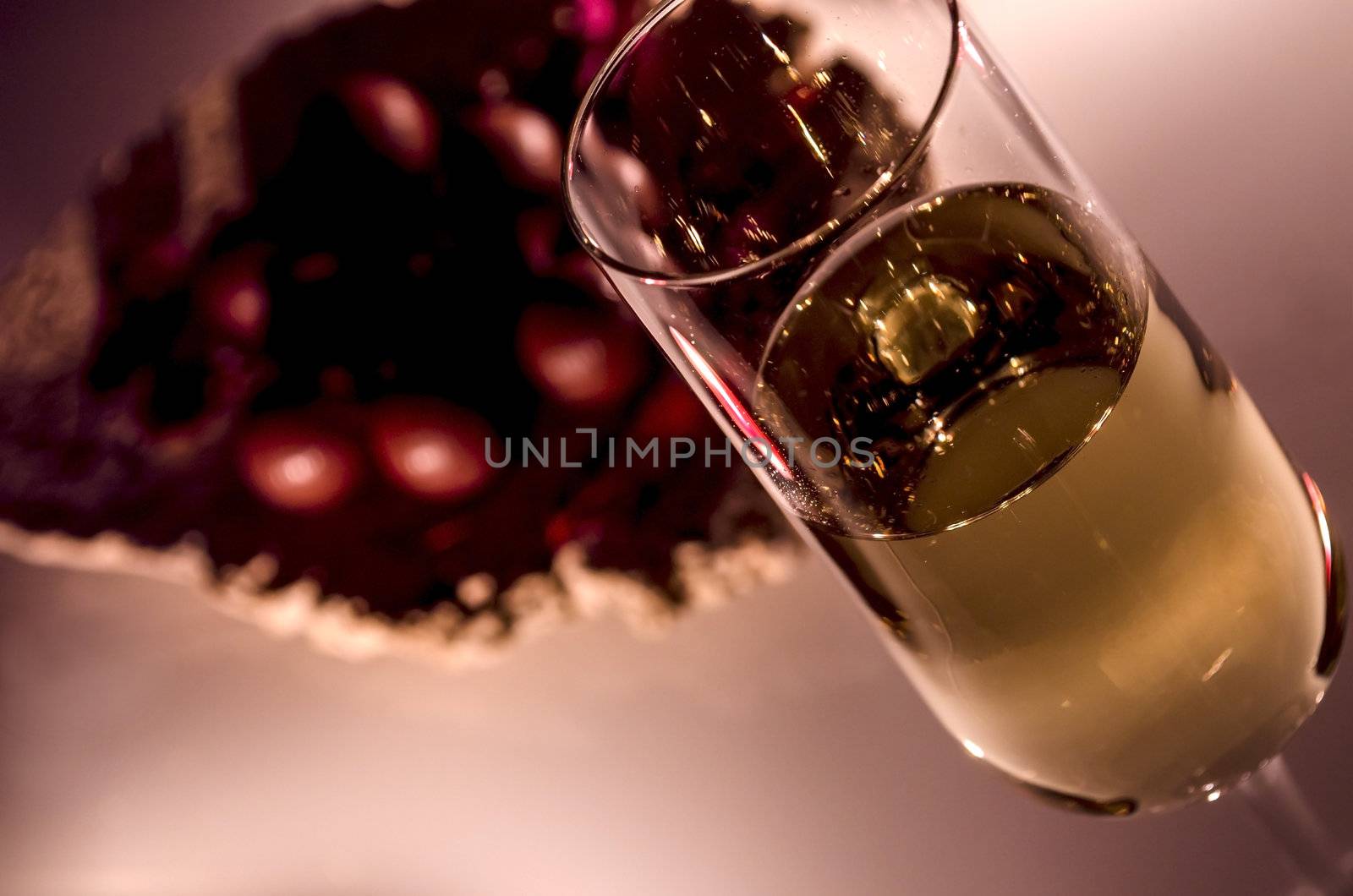 A glass of white wine detail by the candlelight. Represents romantic atmosphere.