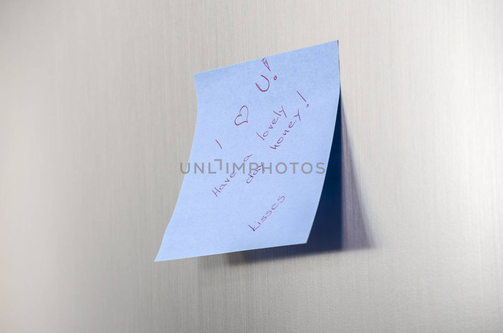 A love you message on a post it note on a stainless fridge.