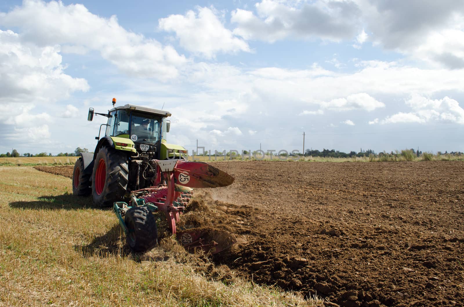 heavy agricultural equipment machine tractor works in rural farm field.