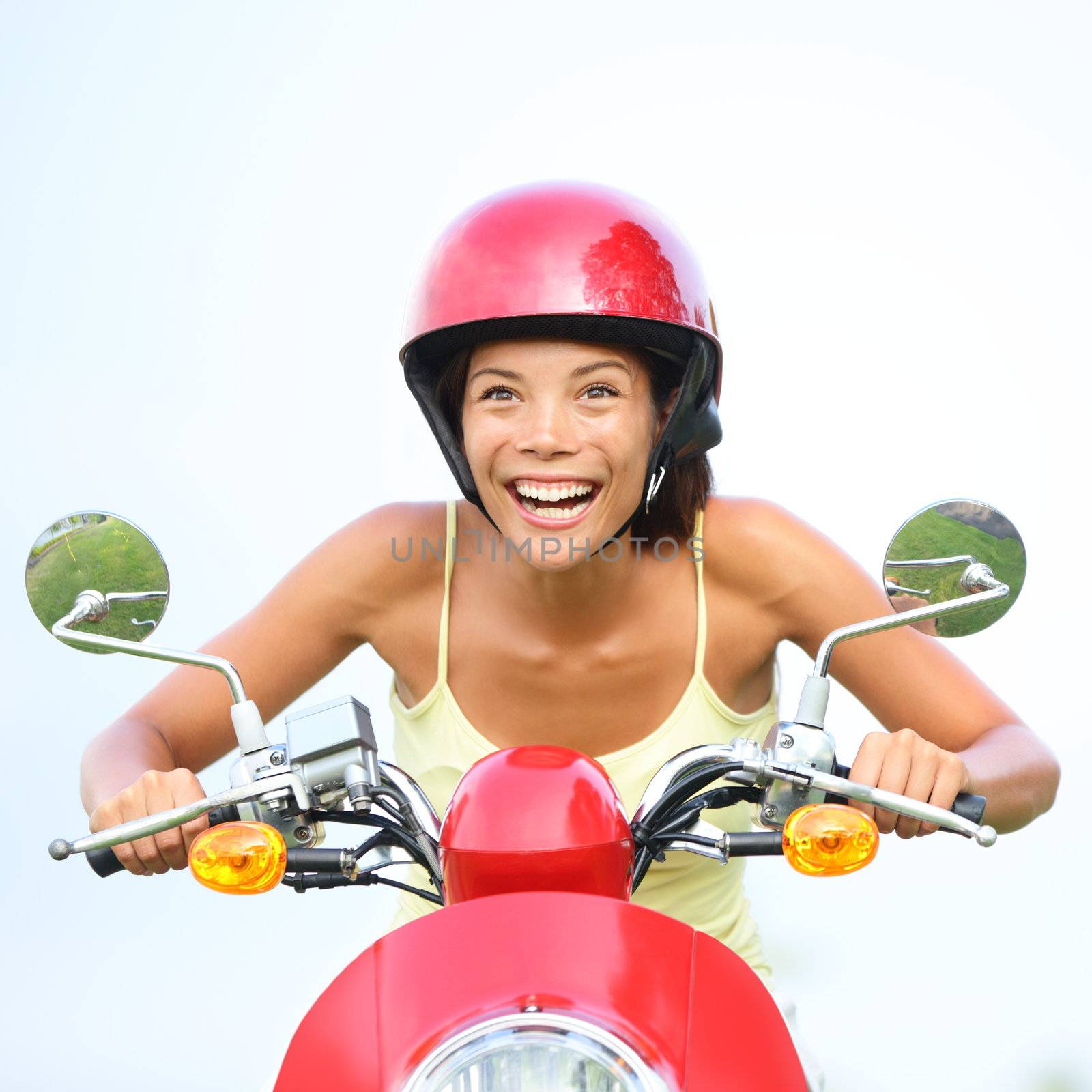Excited woman on scooter happy. Funny portrait of woman driving scooter wearing red helmet. Beautiful mixed race Caucasian / Asian Chinese girl.