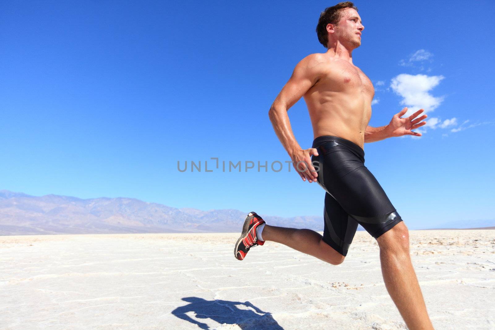 Athlete running sport - fitness runner sprinting in desert shirtless. Fit sports model man during sprint run at great speed under burning sun.