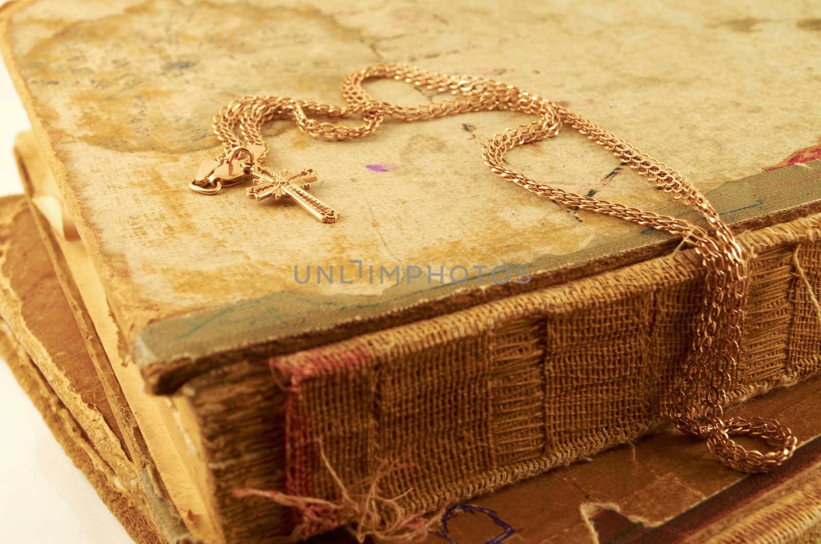 Gold chain with a cross on a background of old battered books