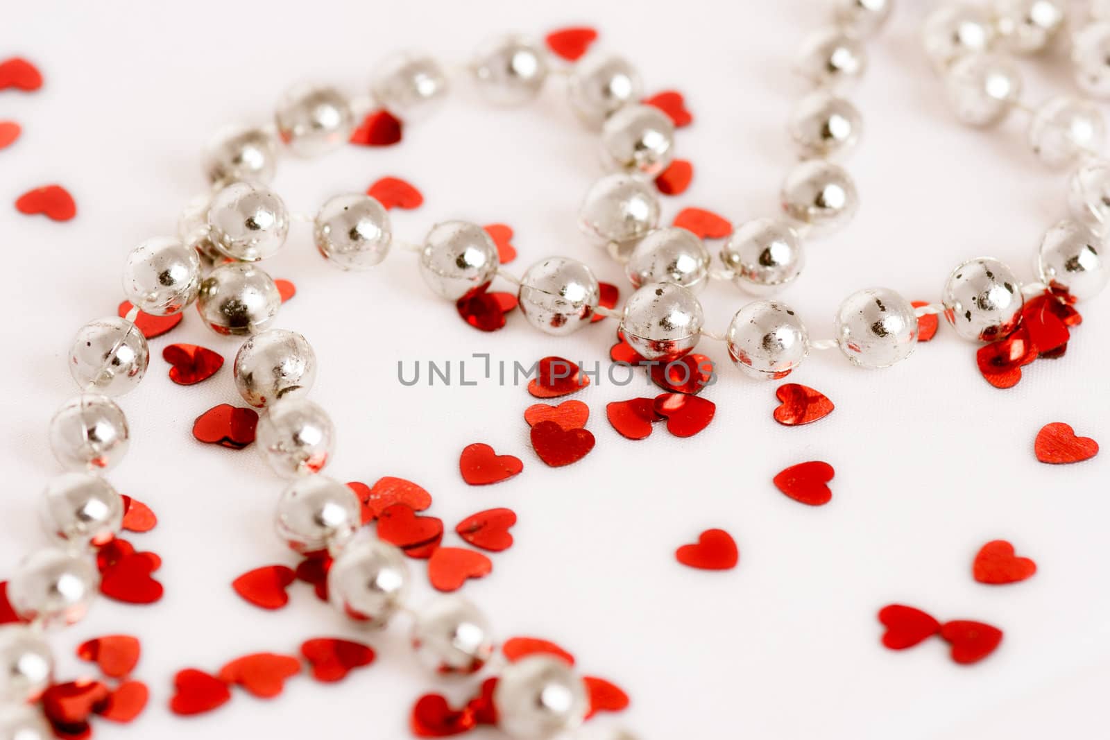 Red glitter hearts on a white background with pearls