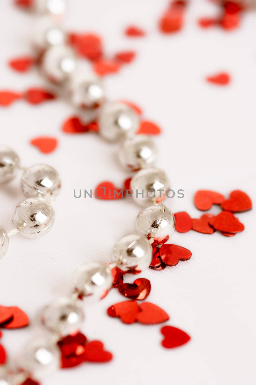 Red glitter hearts on a white background with pearls