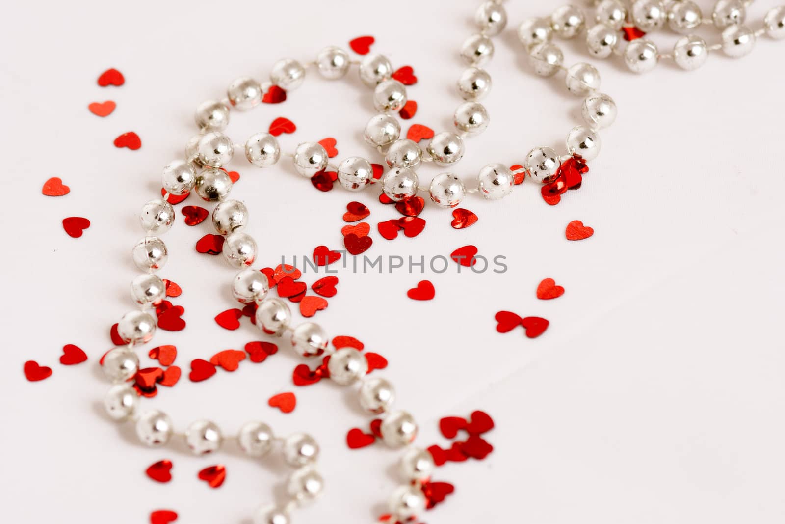 Red glitter hearts on a white background with pearls