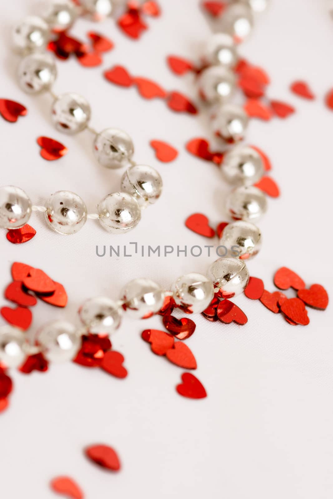 Red glitter hearts on a white background with pearls