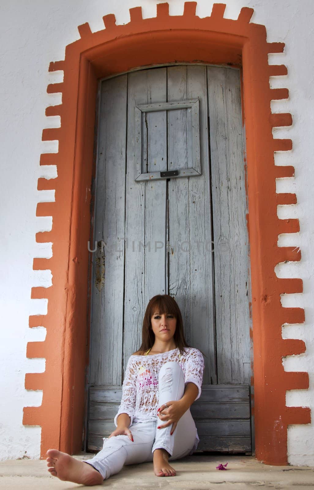 View of a beautiful girl in the beach standing against a house.