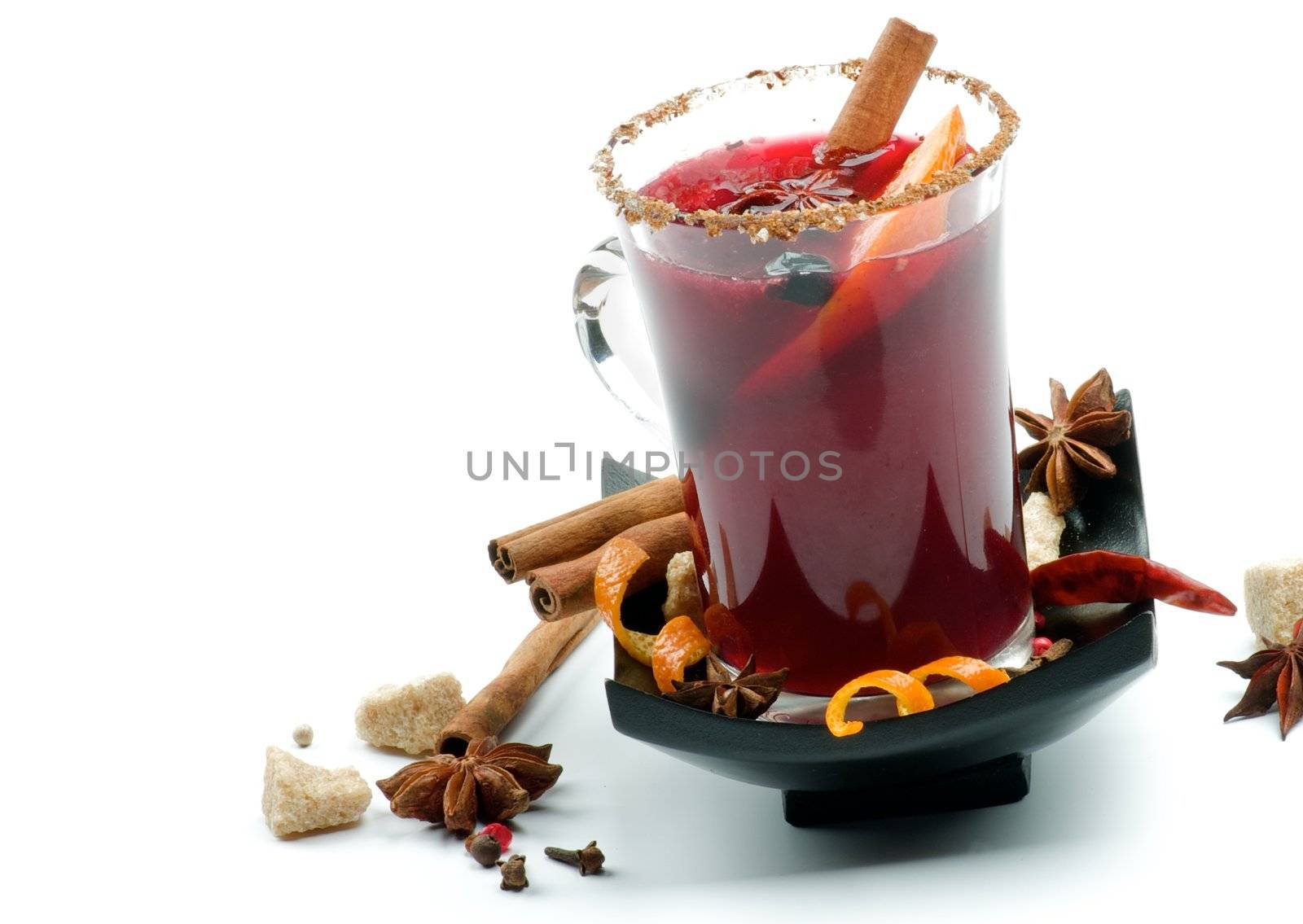 Glass of Mulled Wine and Arrangement of Cinnamon Stick, Orange Rind, Anise Star, Brown Sugar and Spices on Black Saucer closeup on white background