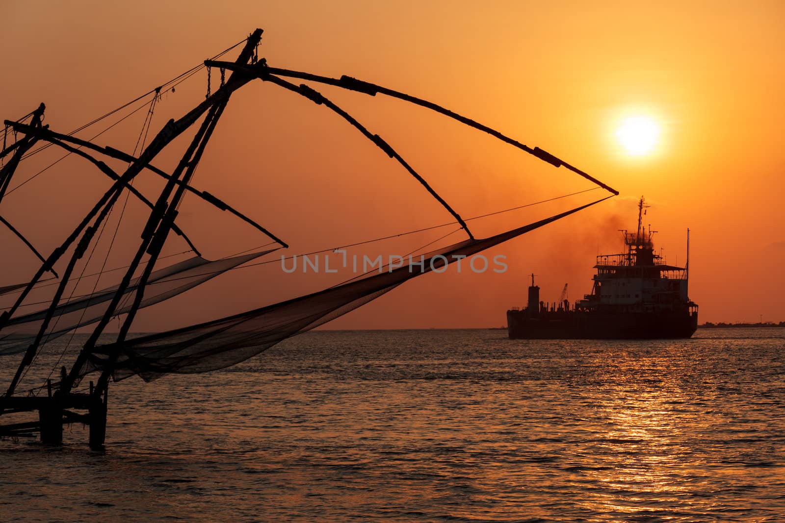 Kochi chinese fishnets on sunset and modern ship. Fort Kochin, Kochi, Kerala, India