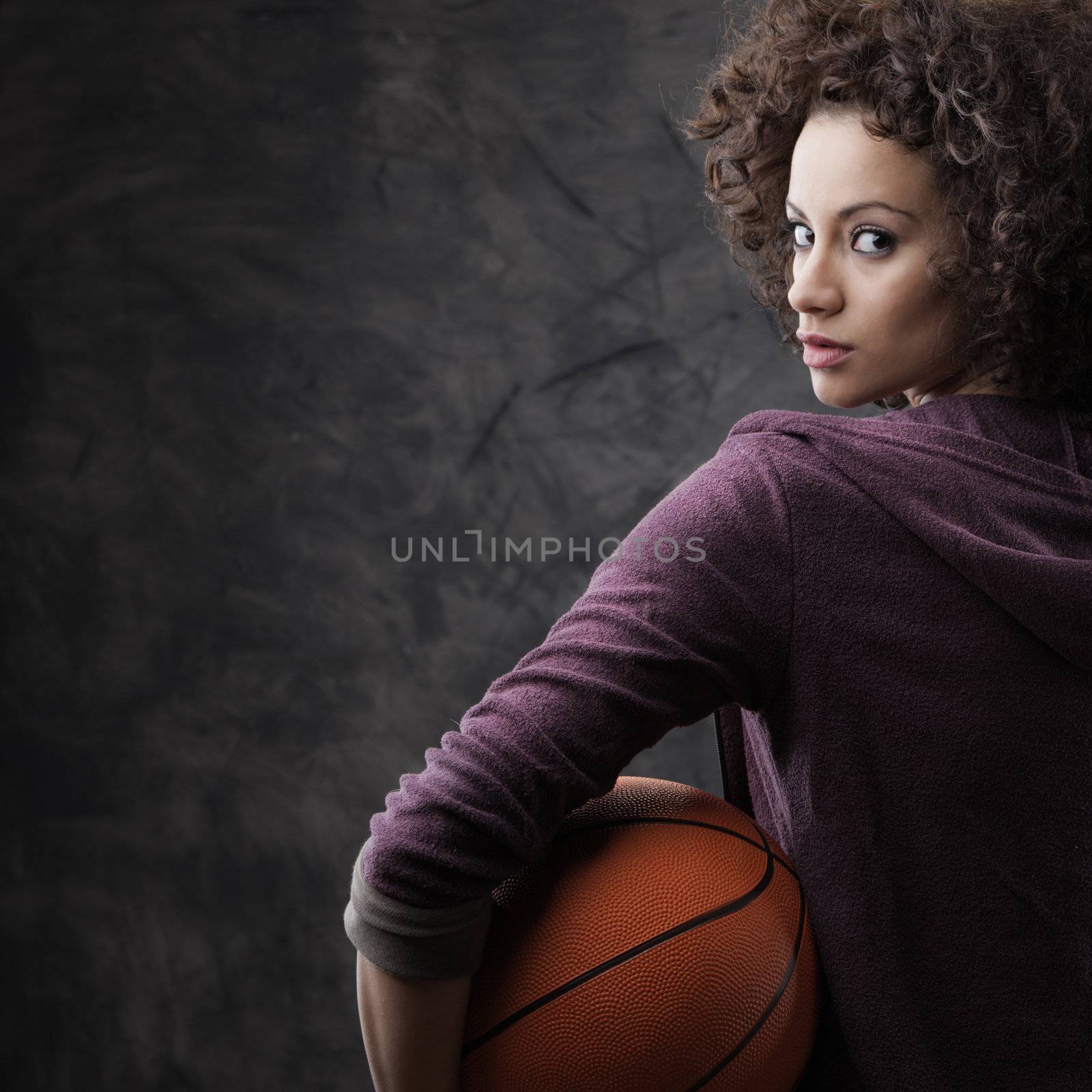 Portrait of young beautiful woman holding a basketball