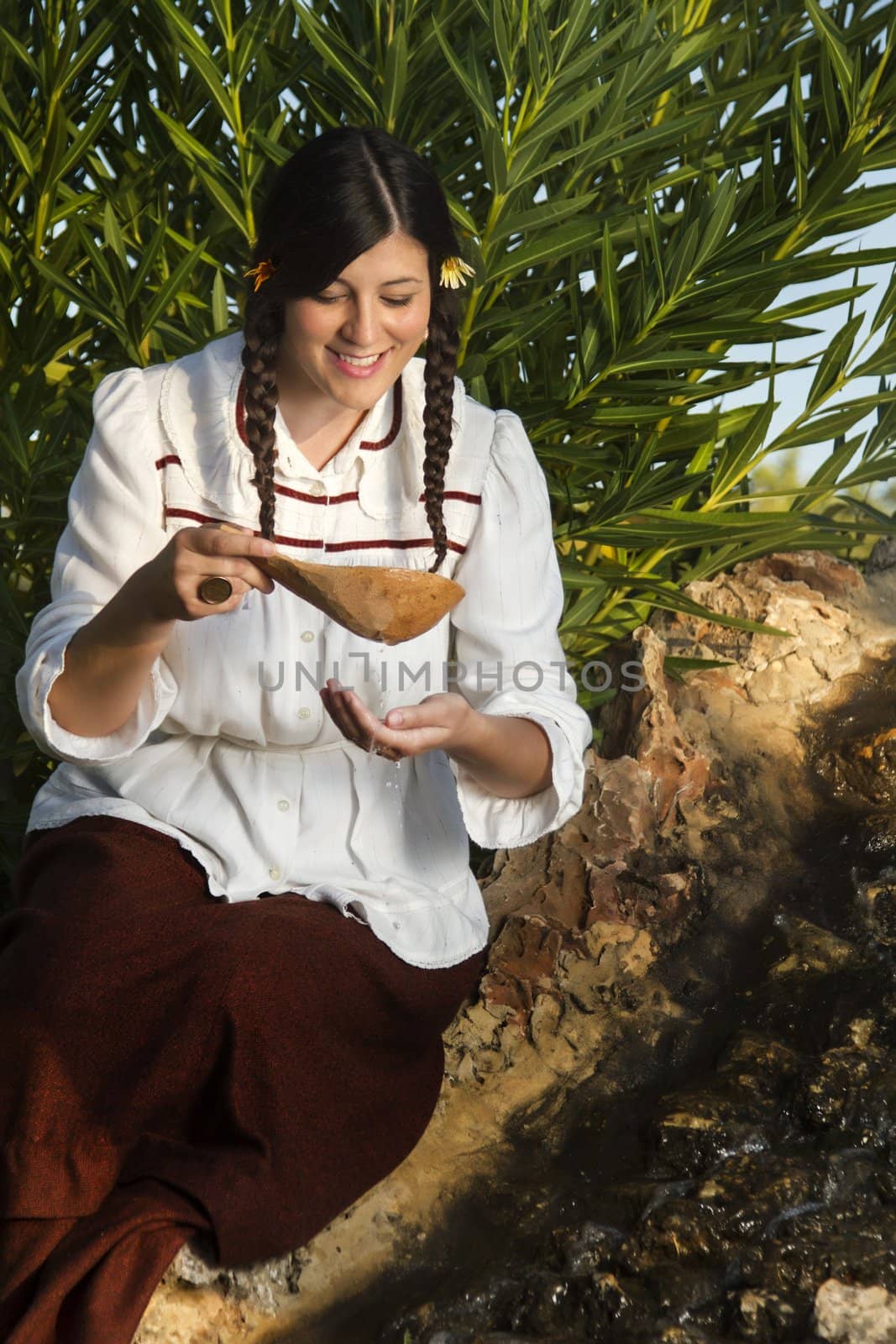 View of a beautiful girl in a classic dress in a countryside set drinking water.